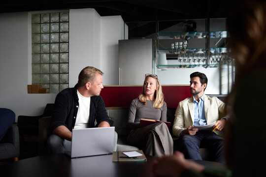 Businesswoman discussing strategy with male colleagues while sitting on sofa