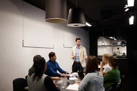 Male entrepreneur discussing strategy with his team sitting around conference table