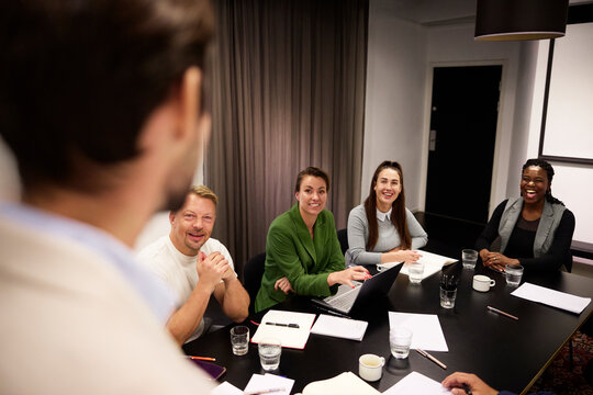 Happy business professionals sharing ideas during meeting in board room