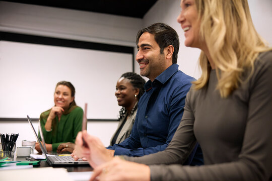 Smiling businessman sitting in group discussion with his team in meeting room