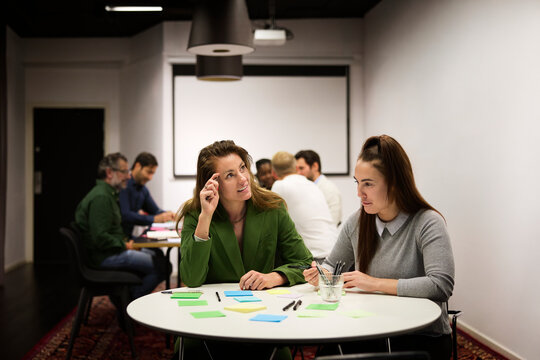 Thoughtful businesswoman sitting with her female colleague in office meeting room