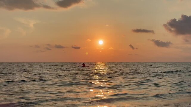 Woman's silhouette on the sup board in the sea at sunset