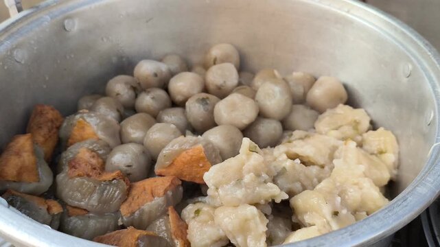 Steamed traditional Indonesian dumplings and tofu inside metal pot steamer

