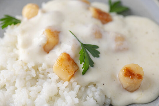 Scallops with cheese sauce and rice on the plate.