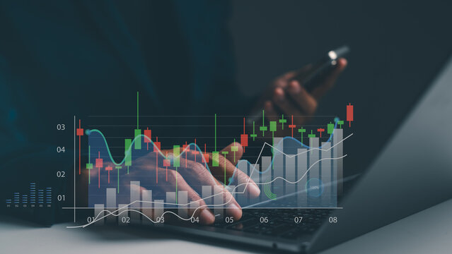 A person uses a laptop and smartphone with transparent financial charts and graphs overlay showing market trends and data analysis.