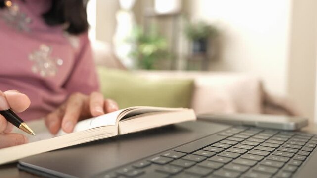 Woman reading book with pen and using smartphone for research at home, combining technology and learning for career development, professional growth, training, skills and modern work.