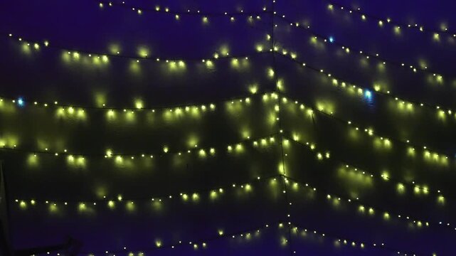 A video of an electric LED string light with a warm yellow-white glow, arranged in horizontal rows against a dark background