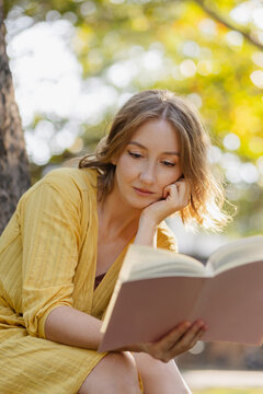 Woman reading book outdoors enjoying nature and education