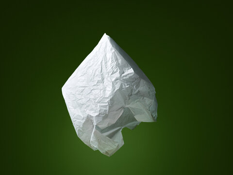 A crumpled plastic bag floats on a green background