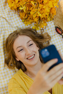 Woman Smiles While Using Smartphone at Picnic