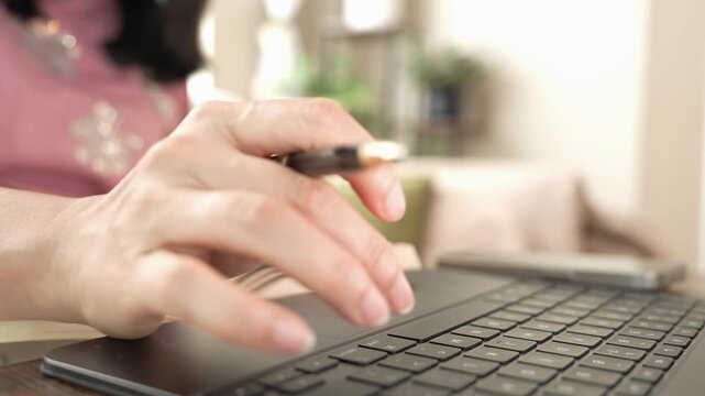 Woman reading a book, checking laptop screen and typing on keyboard at home, doing research and online learning for career development, professional growth, training and modern work skills.
