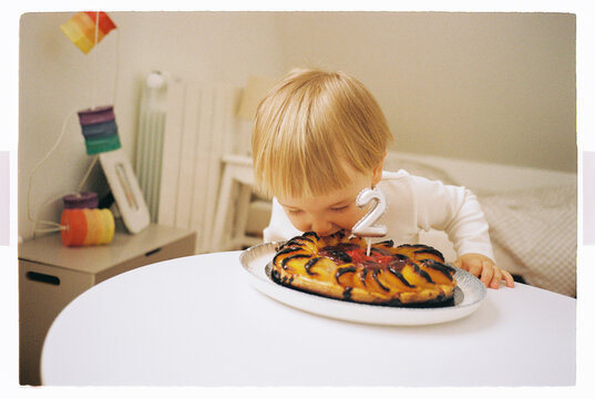 Two year old child taking a bite of his birthday cake
