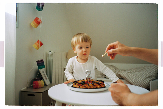 Toddler blowing out candles on a second birthday cake