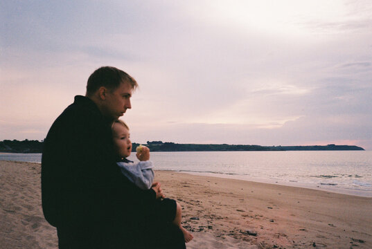 Father holding child on a quiet beach at sunset