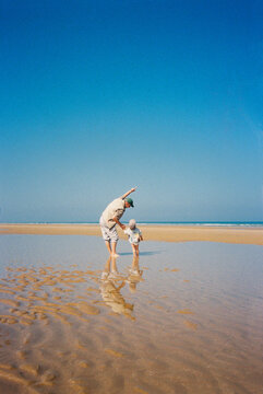 Dad point on sky standing with child in shallow water at low tide