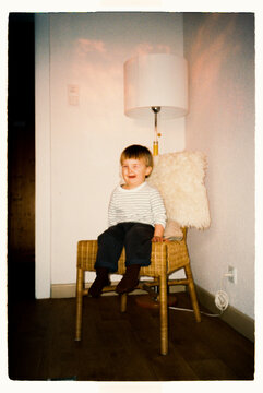 Smiling funny toddler sitting on a vintage woven chair