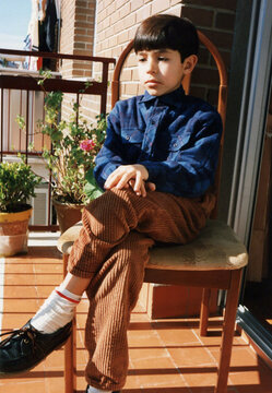 Young boy sitting alone on balcony thinking