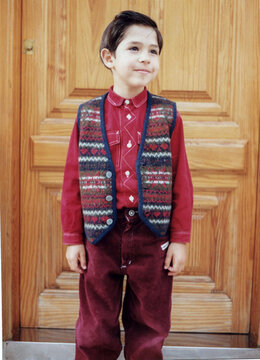 Young boy smiling wearing patterned vest and corduroy pants