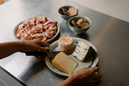 Woman assembles ham, cheese, and bread platter for friends in lodging