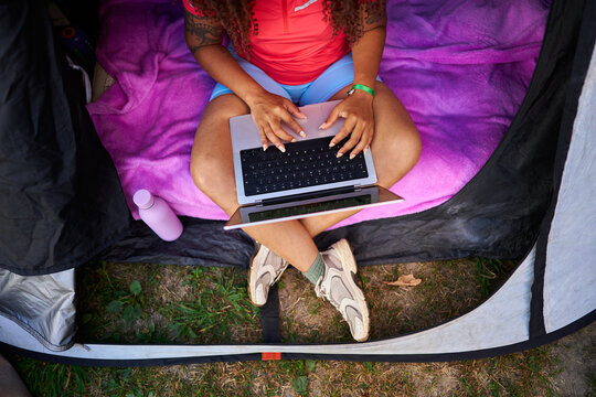 Woman working on laptop inside camping tent