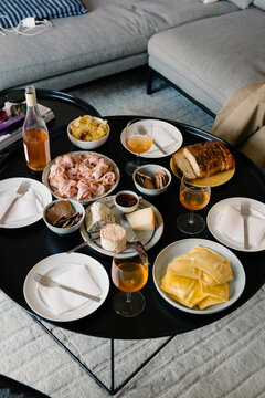Table set with ham, cheese, bread, crackers, and wine