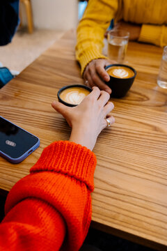 Two people hold cups with latte art on a wooden table in Copenhagen