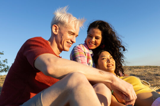 Ffriends having fun lying on a hill in a park at sunset