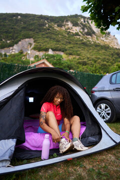 Young woman lacing up shoes inside camping tent