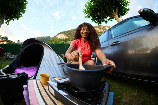 Woman camping cooking healthy food at campsite outdoors