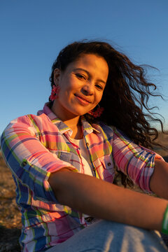 Portrait of woman in sunlight at sunset looking at camera