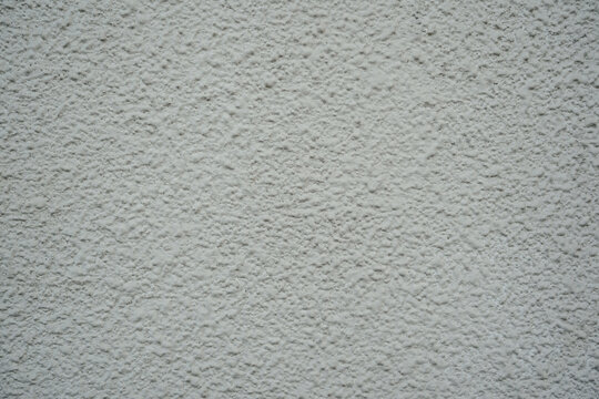 Close up of a white exterior wall with a heavy, bumpy roughcast stucco finish. A clean, uniform architectural texture ideal for blank backdrops and design overlays.