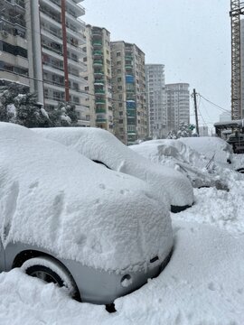 Snow covered cars parked beside apartment buildings after heavy winter snowfall in city street
