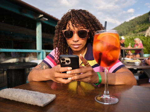 Young woman enjoying spritz cocktail on vacation terrace