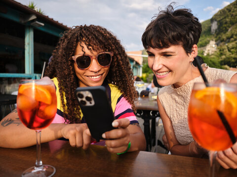 Friends sharing moments, looking at smartphone during aperitif