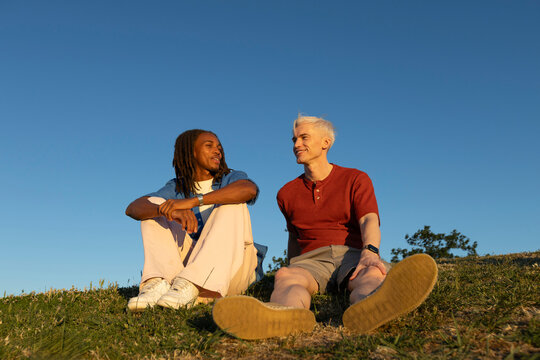 Two male friends hanging out in a hill over blue sky