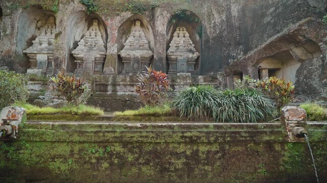 Ancient stone shrines and rock carvings at Gunung Kawi Temple surrounded by lush tropical vegetation in Tampaksiring Bali Indonesia