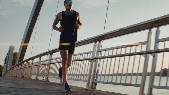 Runner with blade prosthesis trains on modern riverside bridge