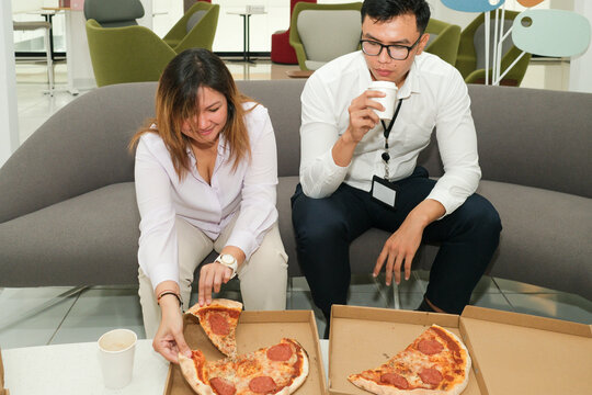 Coworkers enjoying pizza during office lunch break