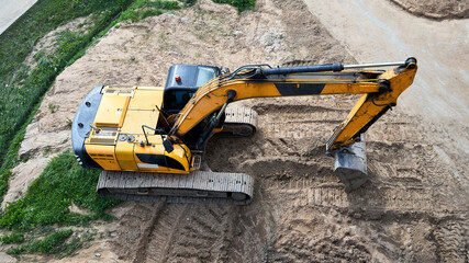 Yellow crawler excavator stands on sand at construction site, top-down view, aerial photography, industrial building machinery works with ground, bucket digs soil on earthworks area © R_Yosha