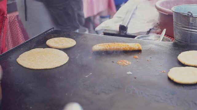 Street food vendor cooking delicious tacos on a comal