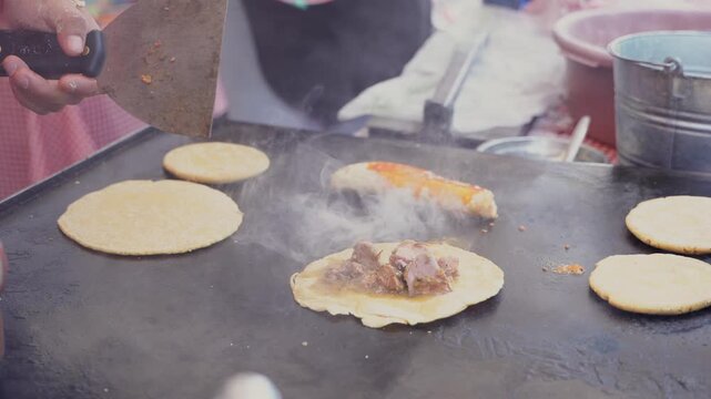 Street food vendor cooking traditional mexican tacos on a griddle