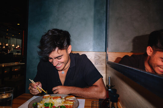 Young man laughing while enjoying a meal out