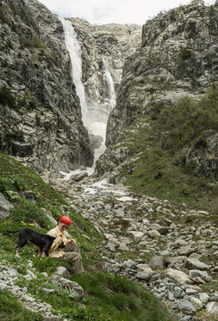 Woman with a dog resting near Ushba Waterfall in Svaneti, Georgia
