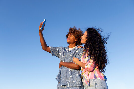 Couple taking selfie over blue sky