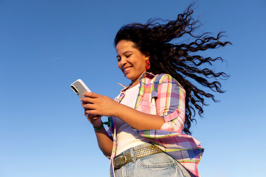 Woman using smartphone over blue sky