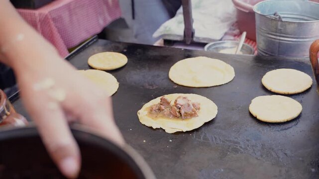 Mexican street food vendor preparing gorditas on comal