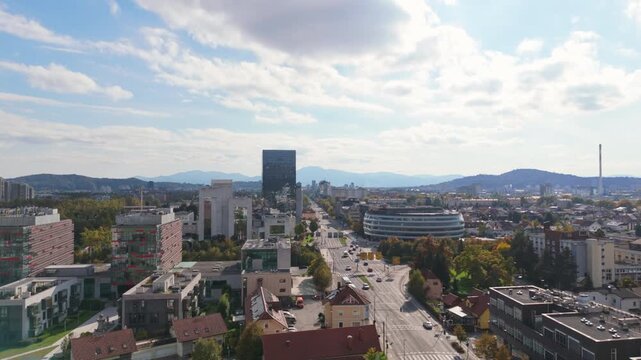 Urban landscape of Ljubljana, Slovenia with buildings and hills under a sunny sky.