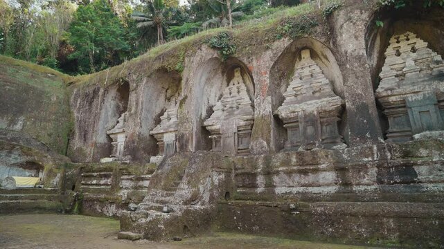 Ancient stone shrines and rock carvings at Gunung Kawi Temple surrounded by lush tropical vegetation in Tampaksiring Bali Indonesia