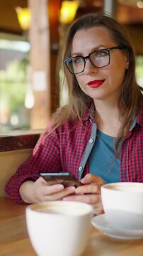 Woman is using smartphone and drinking coffee in the cafe. Slow motion