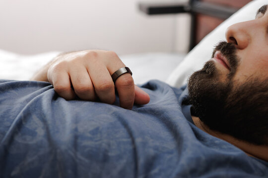 A Man sleeping with a smart ring on his finger. A man sleeping with a smart ring. Smart ring